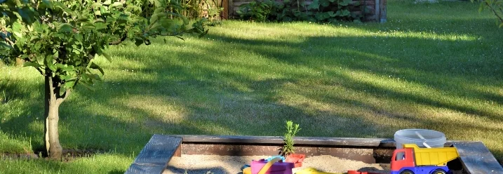 Sandkasten mit Spielzeug im Garten